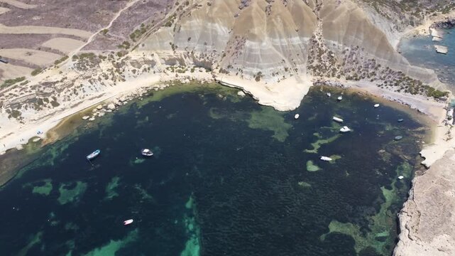 Steep Clay Cliffs in Gozo Malta During Sunny Weather Featuring Earthy Tones and Deep Blue Sea, aerial view near Xatt L-Ahmar salt pans. High quality 4k footage