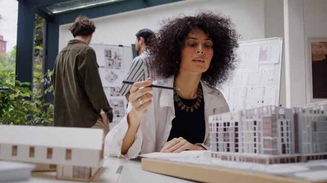 Woman architect carefully examines miniature high-rise building