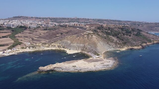Steep Clay Cliffs in Gozo Malta During Sunny Weather Featuring Earthy Tones and Deep Blue Sea, aerial view near Xatt L-Ahmar salt pans. High quality 4k footage