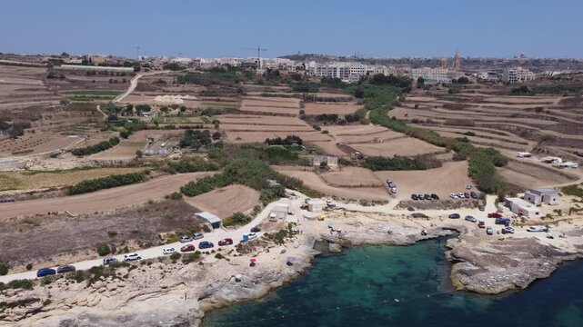 Xatt L-Ahmar, Gozo, Malta. Salt apns. serene aerial view of rocky coastline with sandy beaches and calm waters in natural setting for travel and vacation purposes. stationery perspective from above