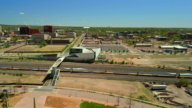 Drone tracking freight train with wind turbine blades moving through downtown Colorado Springs