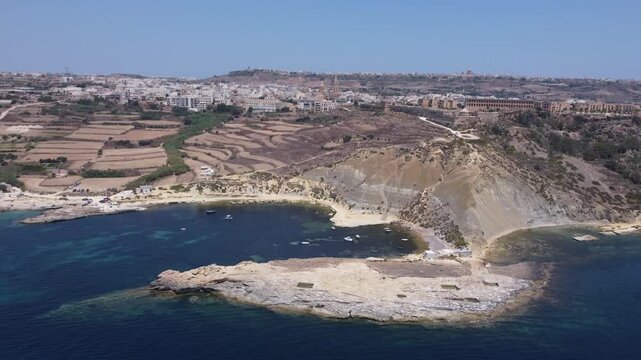 Steep Clay Cliffs in Gozo Malta During Sunny Weather Featuring Earthy Tones and Deep Blue Sea, aerial view near Xatt L-Ahmar salt pans. High quality 4k footage