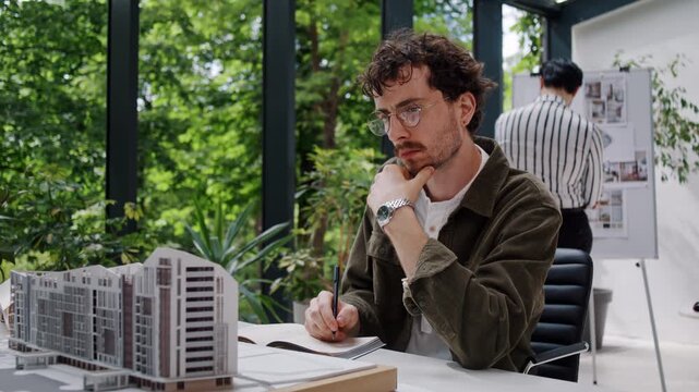 Engineer writes notes about office building model in bureau