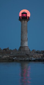 Full strawberry moon rising behind Trakata coastal lighthouse near Euxinograd beach in Varna Bulgaria