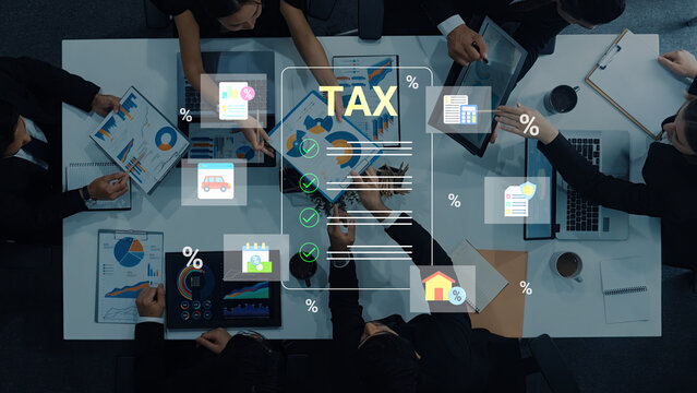 A dynamic overhead view of a professional team discussing tax documents and financial charts, showcasing collaboration and analysis in a modern office environment. Cyphers