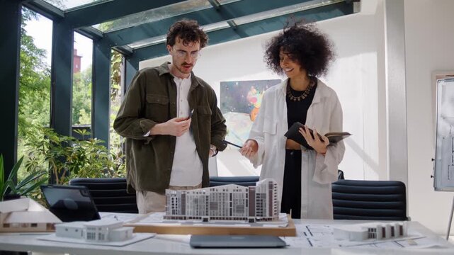 Focused architect designers inspect multistory building model