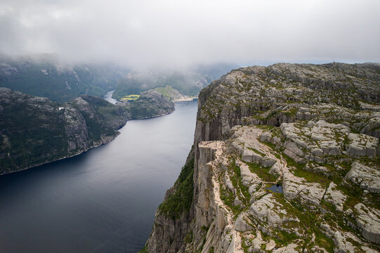 Aerial view of Pulpit Rock, a famous cliff overlooking the Lysefjord, with rocky terrain, lush greenery, and hikers on the plateau in Strand, Rogaland, Norway.