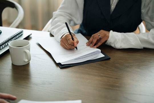 Midsection of businesswoman filling form while sitting at table in office
