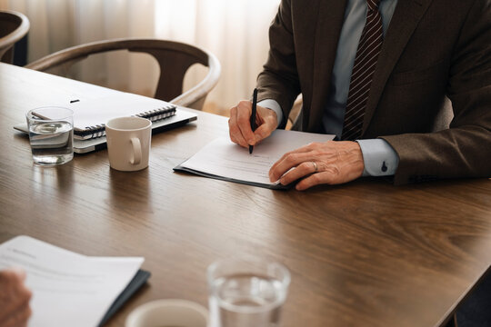Midsection of senior businessman filling form in office