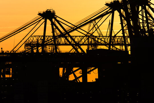 Industrial port cranes and container ship at dusk.