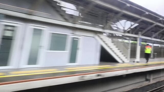 View from a Moving Train Passing Railway Station and Scenic Landscape