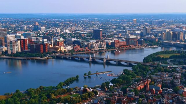 Panoramic view of the Charles River Basin separating Boston and Cambridge, Massachusetts, USA. Drone descends over the waterfront with lots of lush greenery.