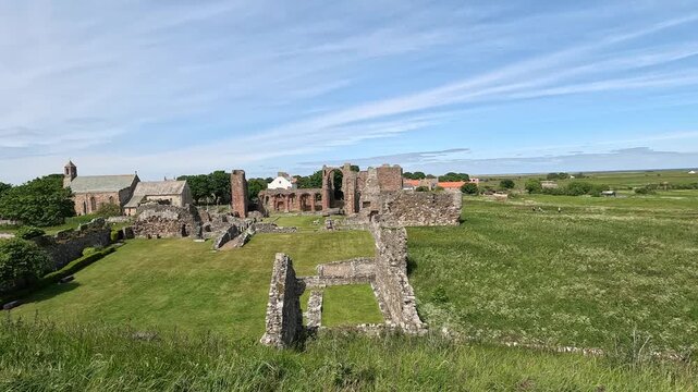 Static view of historic abbey ruins in lush green grass swaying in wind under bright sun, capturing a peaceful timeless landscape.