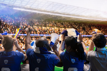 Obraz premium Football supporters in stadium cheering players with megaphone and horns, cheering crowd creates fan chant, using audio equipment to create loud team support.