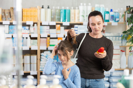 Woman chooses remedy for treating itchy scalp in child. Client reads instructions, organizes self-treatment. Cosmetic and pharmaceutical products for treatment and care.