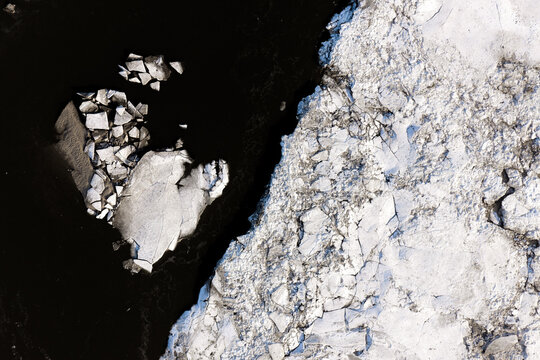 Aerial view of ice floes drifting in the dark waters of the Vistula River within the Zawadowskie Islands Nature Reserve, Masovian Voivodeship, Poland.
