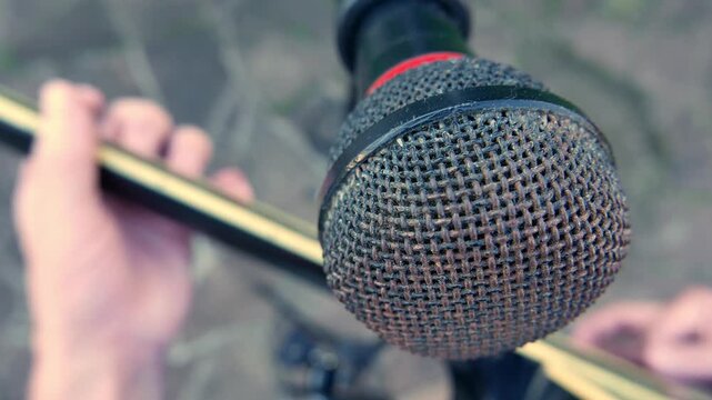 A guitar player (POV, close-up). A musician playing acoustic guitar in front of a microphone. A guitarist strumming a guitar. An artist plucking a guitar. A man playing acoustic guitar.  A singer. 