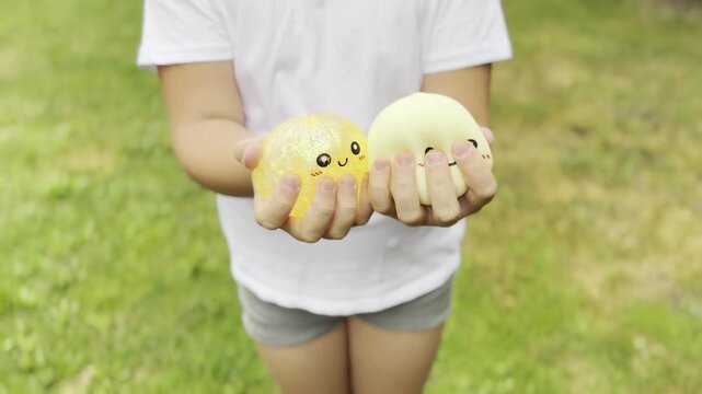 Child holding cute smiley stress balls outdoors
