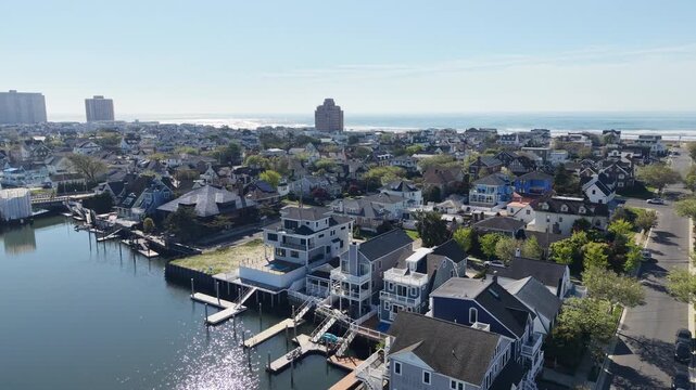 Elevating reveal drone view of a smooth bay with houses and boat slips revealing a beach town and ocean on the other side of the island