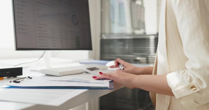 Woman hands in office review analytics documents. She checks finance data and charts on printed sheets, comparing figures for business planning and report. Clear planning and analysis concept.