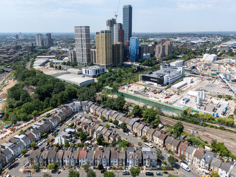 Aerial view of North Acton featuring modern high-rise towers, construction site, and rows of traditional terraced houses near railway tracks in London, England, United Kingdom.