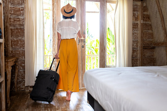Woman with suitcase arriving tropical resort hotel room