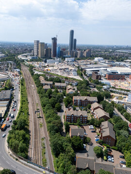 Aerial view of North Acton featuring modern high-rise buildings, railway tracks, and residential areas under a bright sky in London, England, United Kingdom.