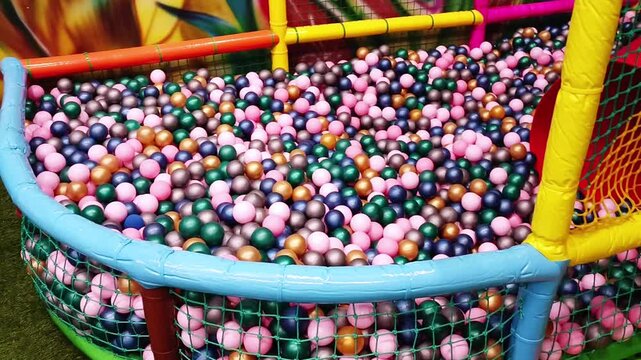 Large ball pit filled with multicolored plastic balls in indoor playground, childrens soft play area, safe jumping fun and active recreation.