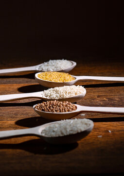Assorted Grains and Cereals in Wooden Spoons on Rustic Wooden Background