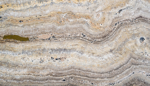 Textura natural de piedra travertino con vetas minerales en tonos beige y grises para fondo abstracto