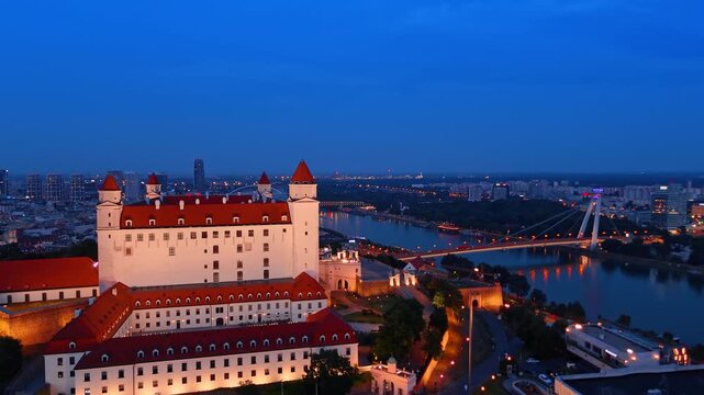 Most SNP bridge over Danube river at night, Bratislava. Aerial shot of illuminated modern suspension bridge with traffic lights.