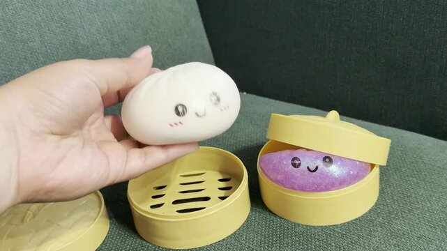 Hand holding cute toy in yellow round container