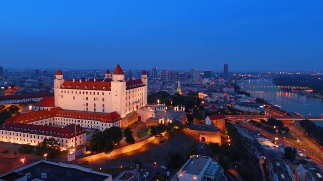 Bratislava castle and SNP bridge across Danube river, Slovakia. High angle view of old fort and illuminated suspension bridge.
