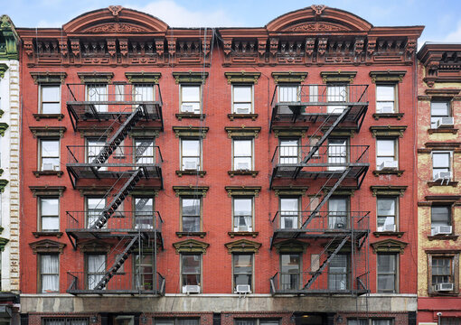 New York City, old apartment building with ornate roof cornice and external fire escape