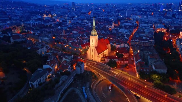 Bratislava Castle and old town aerial view at dusk. Night landscape of glowing medieval fortress on hill surrounded by bright city lights.