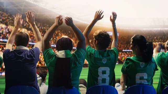 Rear view of football supporters starting crowd wave across packed stadium rows during match for goal celebration, supporter emotion and fan culture content.