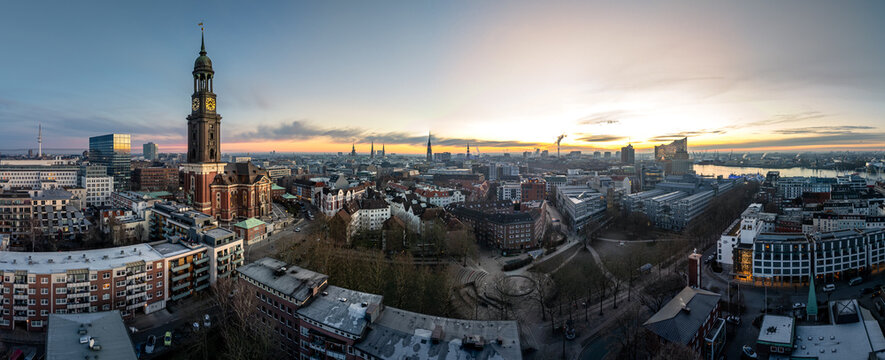 Aerial view of St. Michaeliskirche and the historic cityscape of Hamburg at sunrise, featuring dense urban architecture, rooftops, and the Elbe river, Hamburg, Hamburg, Germany.