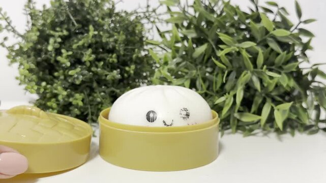 Hand holding cute round soap with a face