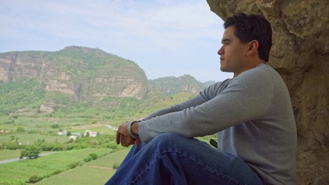 Thoughtful man meditating in cave overlooking valley