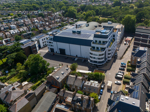 Aerial view of Ealing Studios featuring modern studio buildings with solar panels on the roof, surrounded by residential streets and lush trees in London, England, United Kingdom.