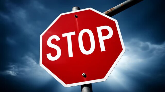 A red octagonal stop sign with white text is mounted on a grey pole under a dramatic cloudy sky