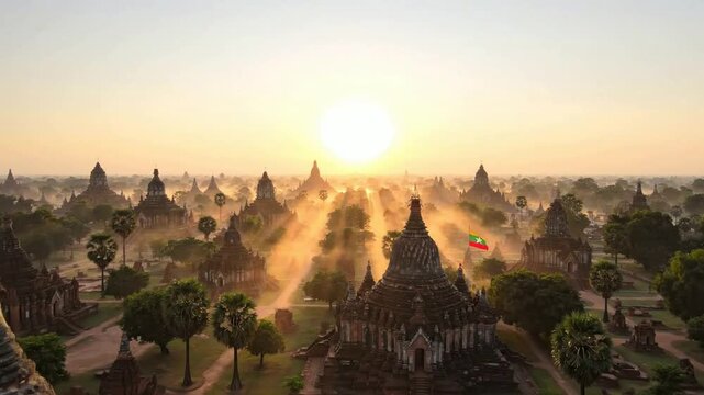 Aerial view of bagan temples at sunrise with myanmar flag waving in golden light, ancient buddhist pagodas landscape in burma