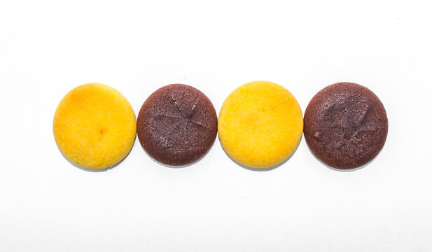 Assorted chocolate cookies and pineapple jam filled cookies isolated on white background. Brown and golden round biscuits arranged in a row