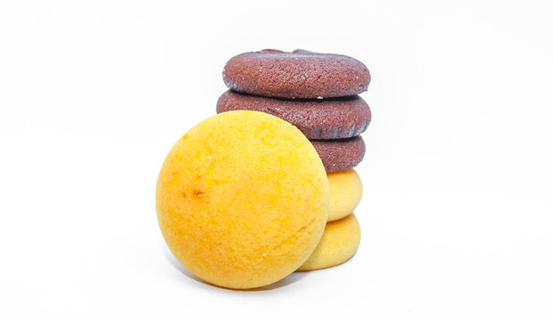 Assorted chocolate cookies and pineapple jam filled cookies isolated on white background. Brown and golden round biscuits arranged in a stack