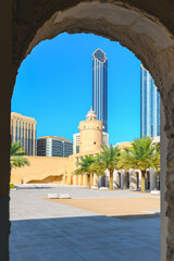 View of the round watchtower with modern skyscrapers behind from a doorway in the Al Hosn Fort, the oldest structure in Abu Dhabi, United Arab Emirates. © Kirk Fisher