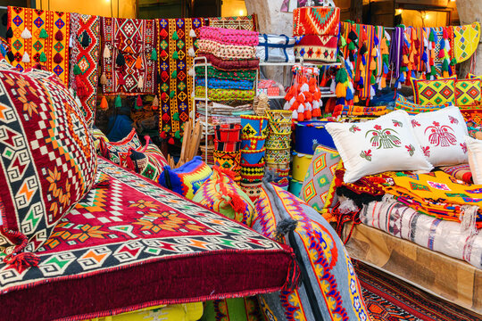 A traditional shop selling colorful textile goods, majlis seating cushions, blankets and decorative Middle Eastern Arabic style rugs and pillows, at Souq Waqif, in Doha Qatar.