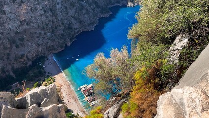 Butterfly Valley beach and turquoise cove seen through rocky cliffs and olive trees from a dramatic high vantage point, Fethiye, Turkey © Faraways