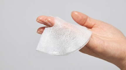 Fototapeta premium Close up of a hand holding a wet wipe with fingers showing through the material