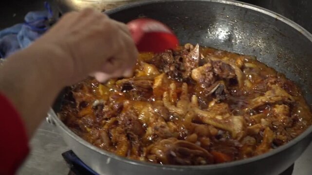 A close-up of a Korean braised or stewed dish with meat and vegetables simmering in a dark pan with rich sauce.