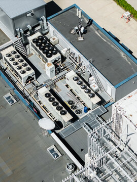 Aerial view of the Datu centrs data center rooftop featuring multiple industrial HVAC cooling units, ventilation systems, and communication antennas in Riga, Latvia.